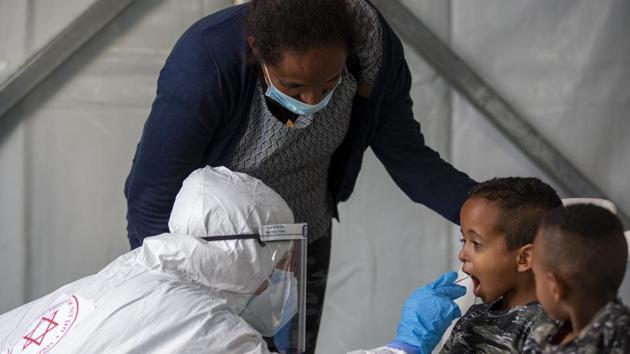 A child is tested by a healthcare worker for the coronavirus at testing center for migrants in Tel Aviv, Israel. (AP) A child is tested by a healthcare worker for the coronavirus at testing center for migrants in Tel Aviv, Israel. (AP)