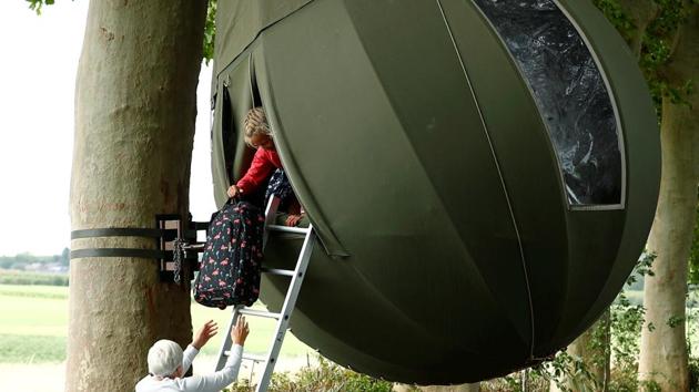 Guests carry their luggage inside a teardrop-shaped tent hanging from a tree created by Dutch artist Dre Wapenaar. (REUTERS/Francois Lenoir)
