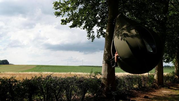 Guests sit inside a teardrop-shaped tent hanging from a tree created by Dutch artist Dre Wapenaar. (REUTERS/Francois Lenoir)