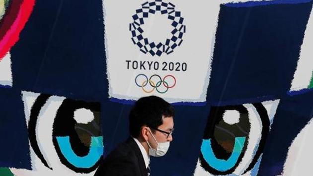 A man wearing a protective mask walks past a large poster featuring Tokyo 2020 Olympic Games mascot Miraitowa.(REUTERS)