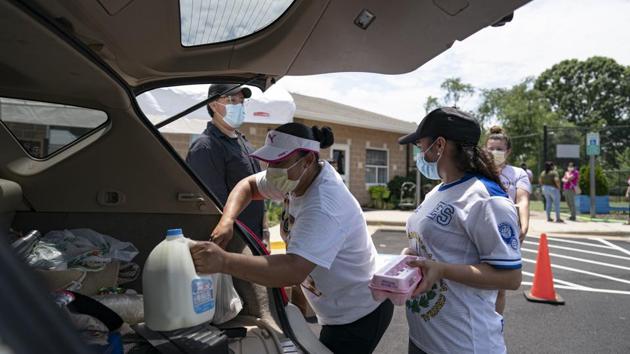 Volunteers place food items in the back of a person's car receiving donations at the Georgetown South Community Center in Manassas, Virginia. On July 7, California, Hawaii, Idaho, Missouri, Montana, Oklahoma and Texas shattered their previous daily record highs for new cases. The biggest jumps occurred in Texas and California, the two largest US states, with more than 10,000 each. (Alex Edelman / Bloomberg)