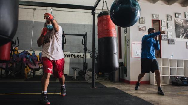 People wearing protective masks work out at a gym in Miami on July 8. In Florida, more than four dozen hospitals across 25 of 67 counties reported their intensive care units had reached full capacity, according to the state’s Agency for Health Care Administration. Only 17% of the total 6,010 adult ICU beds statewide were available on July 7, down from 20% three days earlier. (Jayme Gershen / Bloomberg)