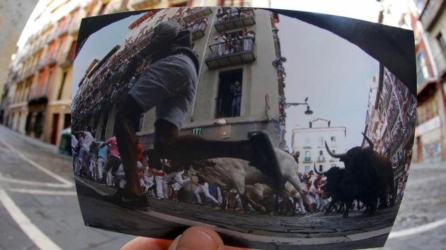 Nazca holds a picture of revellers sprinting in front of bulls and steers during the second running of the bulls at the San Fermin festival, in July 2019. The celebrations start at noon on July 6 and continue until midnight on July 14 every year. Usually, the run is supposed to be completed in a matter of a few minutes, unless something goes wrong.  (Jon Nazca / REUTERS) 