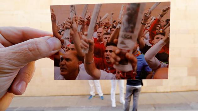 Nazca holds a picture of runners participating in the traditional singing before the running of the bulls at the San Fermin festival in July 2019.  (Jon Nazca / REUTERS) 