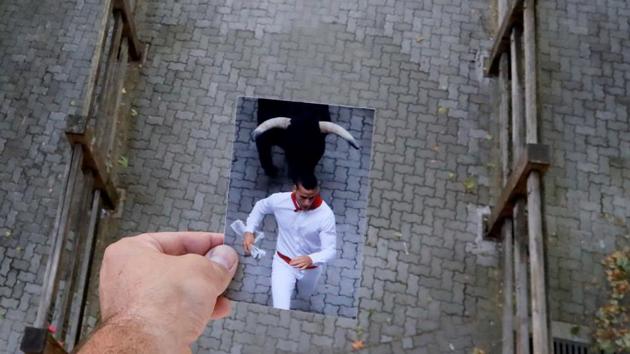 Photographer Jon Nazca holds a picture of a reveller running in front of a bull at the San Fermin festival, from back in July 2019. The photograph was held against the backdrop of the street on July 7-- what would have been the second day of San Fermin festival this year, now cancelled due to the coronavirus outbreak, in Pamplona, Spain. (Jon Nazca / REUTERS) 