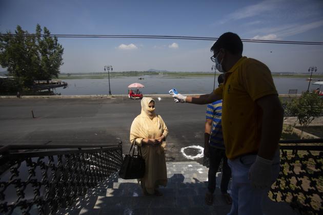 A government employee checks the temperature of a local visitor outside Mughal Garden on the outskirts of Srinagar, Kashmir, Wednesday, July 8, 2020. (AP)
