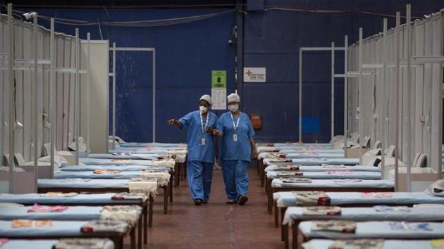 Healthcare workers walk past rows of beds at a makeshift Covid-19 care centre at an indoor sports stadium in New Delhi, on Wednesday.(AP Photo)