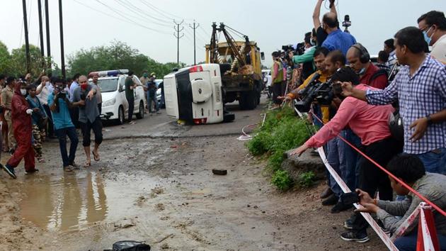 People stand next to an overturned vehicle which was carrying Vikas Dubey, accused of ordering the killing of eight policemen, near Kanpur, in the northern state of Uttar Pradesh.(REUTERS) People stand next to an overturned vehicle which was carrying Vikas Dubey, accused of ordering the killing of eight policemen, near Kanpur, in the northern state of Uttar Pradesh.(REUTERS)
