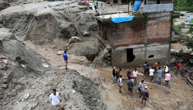 Residents and rescue workers inspect the area outside a house damaged by a landslide and the swell of the Thado-Koshi river due to heavy rains in Jambu village of Sindhupalchok district, some 80 kms northeast of Kathmandu on July 9, 2020. (AFP) Residents and rescue workers inspect the area outside a house damaged by a landslide and the swell of the Thado-Koshi river due to heavy rains in Jambu village of Sindhupalchok district, some 80 kms northeast of Kathmandu on July 9, 2020. (AFP)