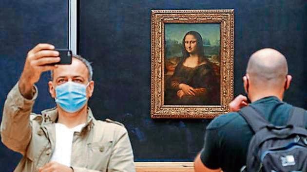 A visitor wearing a face mask takes a selfie in front of Leonardo da Vinci’s masterpiece Mona Lisa at the Louvre Museum in Paris.(AFP)
