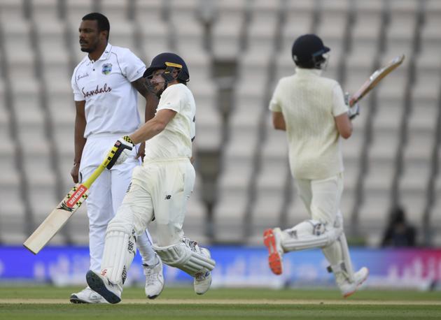 England's Rory Burns, center, and Dom Sibley, right, run past West Indies' bowler Shannon Gabriel to score during the third day of the first cricket Test match between England and West Indies, at the Ageas Bowl in Southampton, England, Friday, July 10, 2020. (Mike Hewitt/Pool via AP) (AP)