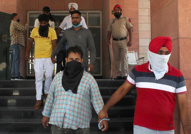 Police with three men who were arrested on Sunday for their involvement in a bank robbery in Mohali on June 17.(HT photo)