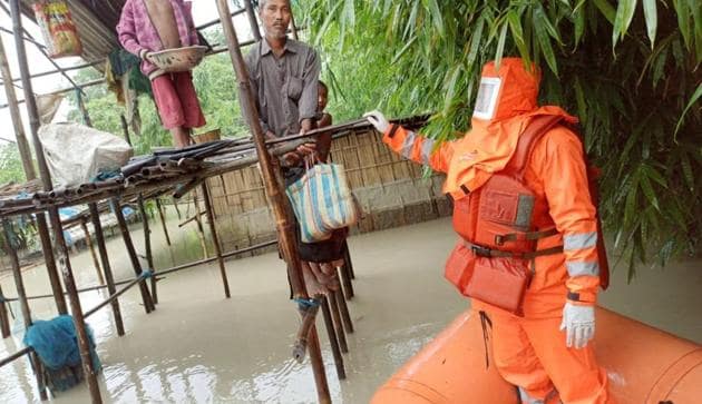 A disaster relief force personnel wearing protective gear rescues a stranded family in Assam’s Barpeta district on Sunday, July 12, 2020.(Photo Credit: Assam State Disaster Management Authority)