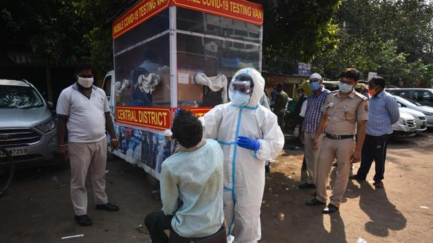 A healthcare worker wearing PPE suit collects swab sample from a man to test for coronavirus infection at Ajmeri Gate in New Delhi, on Saturday.(Sanchit Khanna/HT Photo) A healthcare worker wearing PPE suit collects swab sample from a man to test for coronavirus infection at Ajmeri Gate in New Delhi, on Saturday.(Sanchit Khanna/HT Photo)