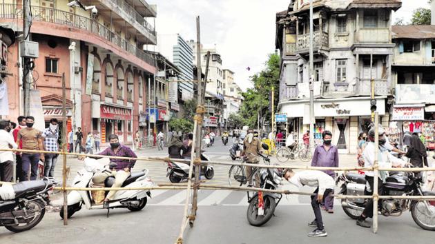 People cross a road recently barricaded on Laxmi road on Sunday, ahead of the lockdown from Monday, midnight. (Rahul Raut/HT Photo) People cross a road recently barricaded on Laxmi road on Sunday, ahead of the lockdown from Monday, midnight. (Rahul Raut/HT Photo)