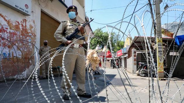 Security forces personnel stand guard in the COVID containment zone of Gole Pulli in Jammu.(PTI)