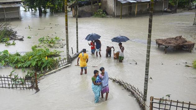 Villagers wade through a waterlogged street after their house were submerged, in Pathsala on July 12. Embankments, roads, bridges, culverts and other infrastructure have been damaged at various places in Lakhimpur, Biswanath and Dhemaji districts, thus affecting the pace of the rescue operations, the ASDMA told PTI. (PTI)