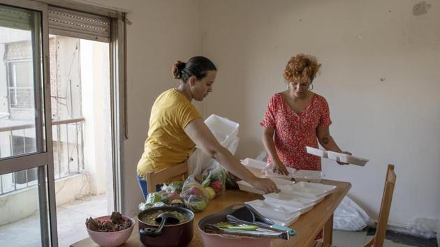 Basma Mostafa, a 30-year-old journalist who founded an initiative that sends freshly home cooked meals to quarantined coronavirus patients, right, and Fatma Youssef, a volunteer, left, package food into boxes, at an apartment, in Cairo, Egypt.(AP)