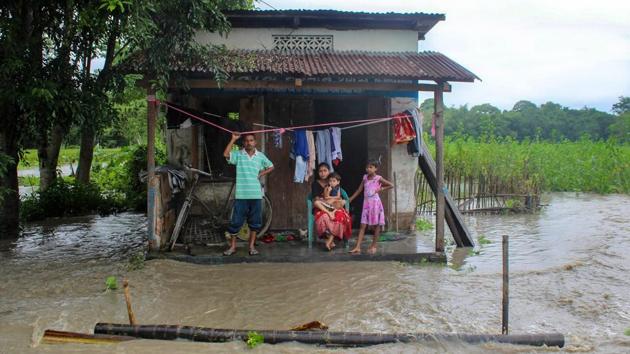 A flood affected family takes shelter at the doorstep of a shop at Manahkuchi in Kamrup district of Assam on July 12. As a result of rising water levels, houses have been inundated in the area, forcing residents to move to safety. (PTI)