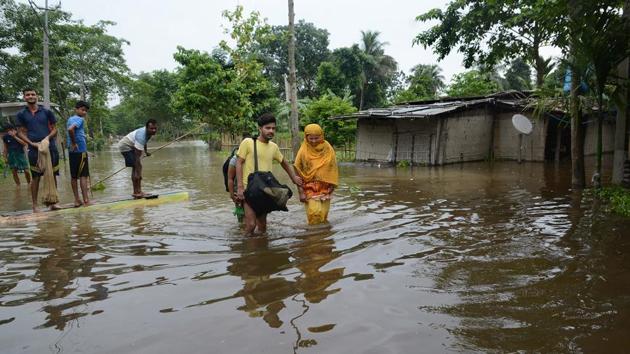 People walk through a flooded locality in Domdoma to safer places on July 13. According to a PTI report, Dhemaji, followed by Barpeta and Lakhimpur continue to be the worst flood affected districts so far. (PTI)