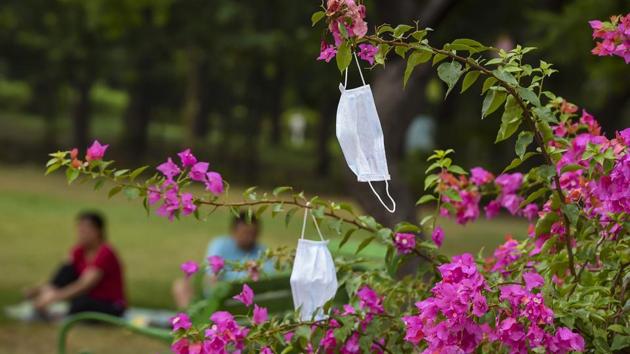 Face masks are seen hanging on the branches of a tree in the backdrop of people exercising at Nehru Park in New Delhi.(PTI File Photo)