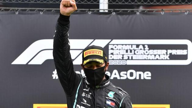 Mercedes' Lewis Hamilton wears a protective face mask as he celebrates winning the race on the podium.(REUTERS)