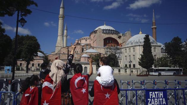 People draped in Turkish flags stand outside the now closed Byzantine-era Hagia Sophia, one of Istanbul's main tourist attractions in Istanbul on July 11. Turkey's President Recep Tayyip Erdogan formally reconverted Hagia Sophia into a mosque and declared it open for Muslim worship on July 10, hours after a High Court annulled a 1934 decision that had made the religious landmark a museum. (Emrah Gurel / AP)