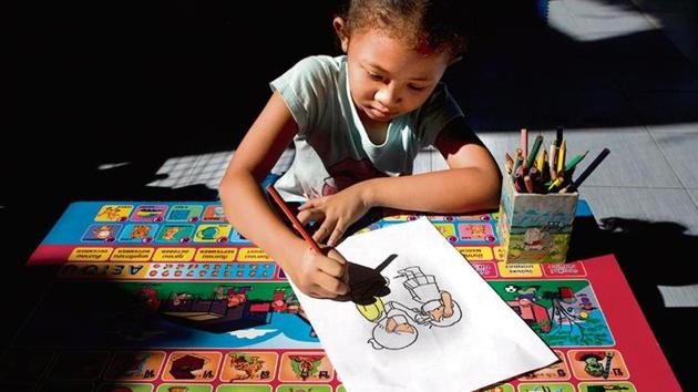 A girl colours a sketch made to educate children on Covid-19 in Bangkok, Thailand.(AP Photo)