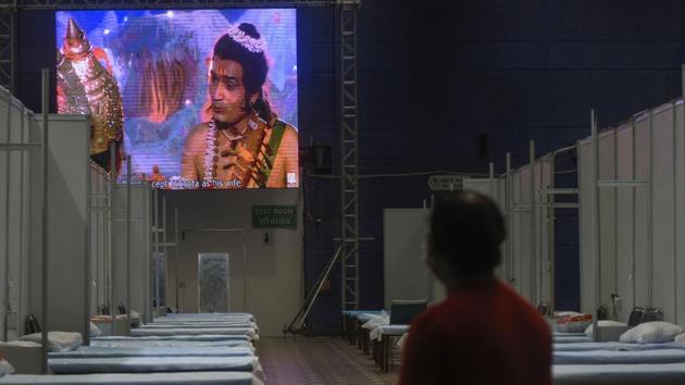 A Covid-19 patient watches a mythological show playing on a screen at the Commonwealth Games Village Covid-19 care centre in New Delhi on July 12. Government reports on July 13 showed, as many as 11,130 Covid beds in hospitals were vacant against the total of 15,359 beds.  (Biplov Bhuyan / HT Photo) 