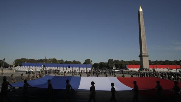 Soldiers hold a French flag during a rehearsal for the Bastille Day parade on the Concorde square in Paris Monday, July 13, 2020. (AP Photo/Christophe Ena)