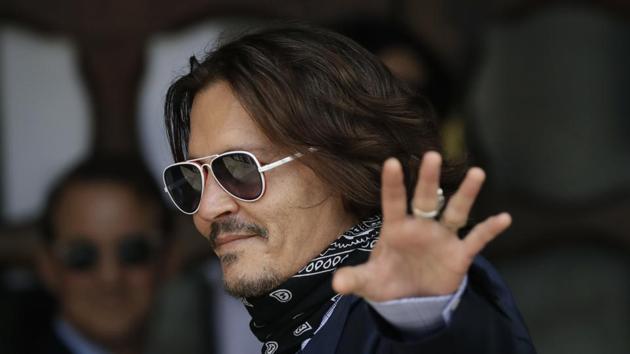 Johnny Depp gestures to the media as he arrives at the High Court in London.(AP)