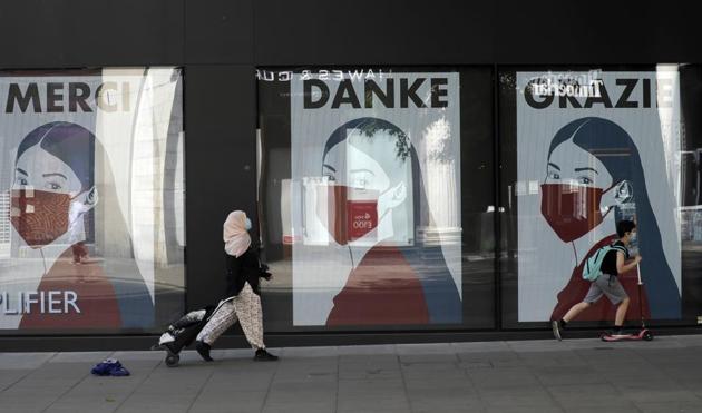 FILE - In this Thursday, May 21, 2020 file photo, a woman and child wearing face masks past a coronavirus related artwork displayed on screens in the window of the Flannels clothing store on Oxford Street, in central London. (AP) FILE - In this Thursday, May 21, 2020 file photo, a woman and child wearing face masks past a coronavirus related artwork displayed on screens in the window of the Flannels clothing store on Oxford Street, in central London. (AP)