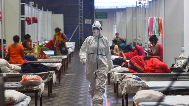 A health worker in PPE walks past Covid-19 patient housed inside the Commonwealth Games Village Sports Complex which is temporarily converted into a coronavirus care centre at Patparganj in New Delhi on Tuesday.(Sanchit Khanna/HT Photo)