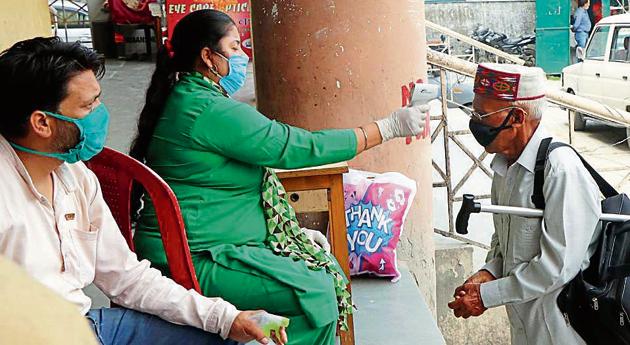 A health worker screens a passengers at the bus stand in Mandi on Wednesday. (Birbal Sharma/HT) A health worker screens a passengers at the bus stand in Mandi on Wednesday. (Birbal Sharma/HT)