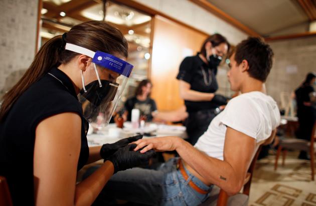 A model and dressers are seen at the backstage of the Etro Spring/Summer 2021 Men's collection and Women's pre-collection livestreamed show at the Four Seasons hotel, amid the coronavirus disease (COVID-19) outbreak, during Milan Digital Fashion Week in Milan, Italy, July 15, 2020. (REUTERS)