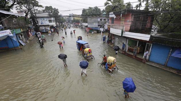 People make their way through flood waters in Sunamgong on July 12. In the northern town of Biswambharpur, villagers told AFP that most of the houses were partly underwater after the Surma, a major river in northeast Bangladesh, burst its banks. (Sultan Mahmud / AFP) 