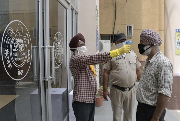 Staff conducting thermal screening of visitors at municipal corporation’s Zone D office in Ludhiana on Wednesday. (HARSIMAR PAL SINGH/HT)