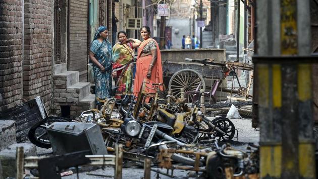 Women stand beside charred remains of vehicles and vandalised properties at Shiv Vihar in northeast Delhi on March 2, 2020.(PTI File Photo)