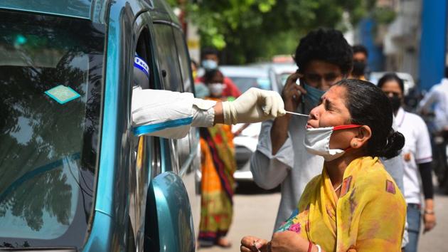 A health worker of Special Mobile Surveillance team in PPE coveralls collects a swab sample from a woman for Covid-19 rapid antigen test at Model Town in New Delhi on Wednesday.(Sanchit Khanna/HT PHOTO)