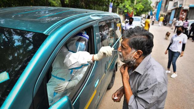 A health worker of Special Mobile Surveillance team in PPE coveralls collects a swab sample from a man for Covid-19 rapid antigen test, at Model Town in New Delhi on Wednesday.(Sanchit Khanna/HT PHOTO)