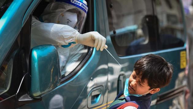 A health worker of Special Mobile Surveillance team in PPE coveralls attempts to collect a swab sample from a child for Covid-19 rapid antigen test at Model Town in New Delhi on Wednesday.(Sanchit Khanna/HT PHOTO) A health worker of Special Mobile Surveillance team in PPE coveralls attempts to collect a swab sample from a child for Covid-19 rapid antigen test at Model Town in New Delhi on Wednesday.(Sanchit Khanna/HT PHOTO)
