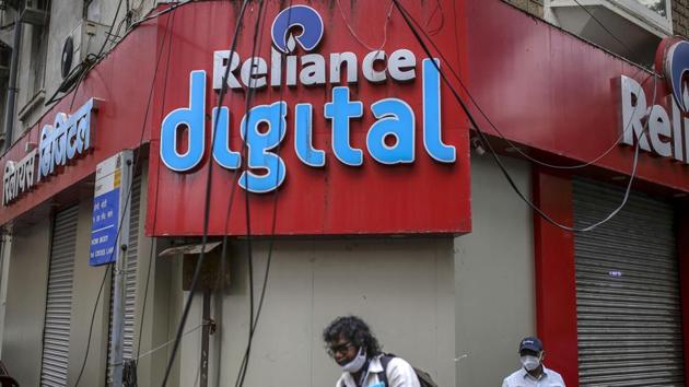 Pedestrians walk past a store of Reliance Digital Retail Ltd., a subsidiary of Reliance Industries Ltd., in Mumbai.(Bloomberg File Photo)