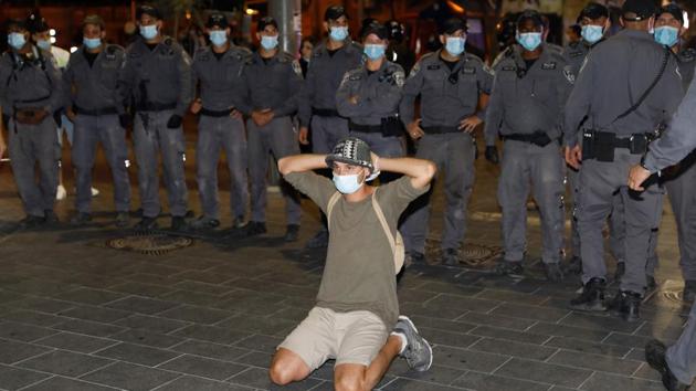 A protester kneels in front of a row of police officials after the protest on July 14. 50 protesters were arrested following the protest. Addressing the protest, Netanyahu said he respected the right to demonstrate but that there was “no place” for violence or ignoring public safety rules on social distancing, reported AP. (Menahem Kahana / AFP)