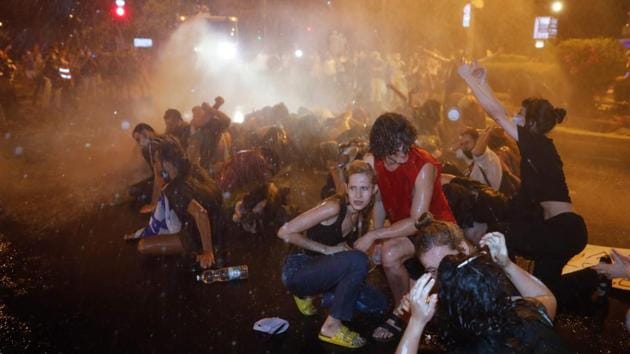 Israel police use water cannons as they clash with protesters outside the Prime Minister’s residence on July 14. As the demonstration was ending, there were small scuffles between police and some protesters. Police told AP that protesters threw stones and eggs and vandalized shops while the police was trying to restore order. (Menahem Kahana / AFP)