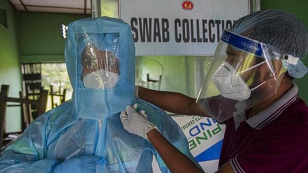 A health worker helps another to wear personnel protection equipment before he collects nasal swab samples at a Covid-19 testing centre in Guwahati, Assam.(AP) A health worker helps another to wear personnel protection equipment before he collects nasal swab samples at a Covid-19 testing centre in Guwahati, Assam.(AP)
