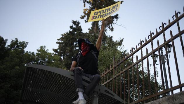 A demonstrator holds a sign that reads “You are detached. We are fed up.” outside Prime Minister’s residence, on July 14. According to AP, the rowdy demonstration on July 14 was led by anti-corruption activists who refer to Netanyahu as the “crime minister.” (Ariel Schalit / AP)