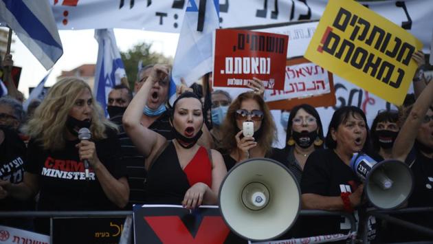 Demonstrators, defying orders to maintain social distancing requirements, chant slogans and blow horns in Jerusalem on July 14. Thousands of Israelis held banners saying “We’re fed up with you, Bibi.” The demonstrators called for Netanyahu ‘s resignation as Israel’s number of reported coronavirus cases reached 44,188. (Ariel Schalit / AP)