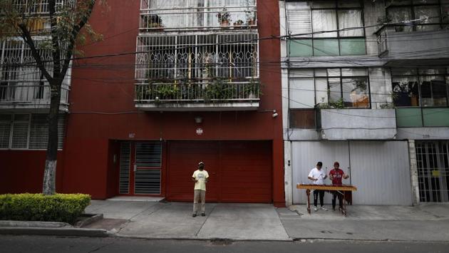 Brothers Alexis De Jesus Nanguelu, 23, right, and Cristhian Omar Nanguelu, 17, perform on the marimba as their uncle Arturo Lezama looks for residents willing to toss a coin out of an apartment window to tip them, in the Roma Norte neighborhood of Mexico City. (AP Photo/Rebecca Blackwell) Brothers Alexis De Jesus Nanguelu, 23, right, and Cristhian Omar Nanguelu, 17, perform on the marimba as their uncle Arturo Lezama looks for residents willing to toss a coin out of an apartment window to tip them, in the Roma Norte neighborhood of Mexico City. (AP Photo/Rebecca Blackwell)