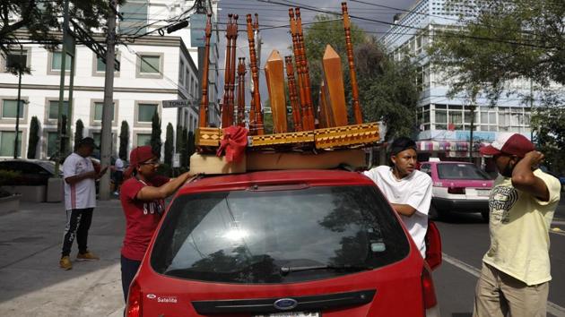 Brothers Alexis De Jesus Nanguelu, 23, left, and Cristhian Omar Nanguelu, 17, secure two marimbas on the roof of the family's car, as they leave after performing in various city blocks to collect tips from appreciate residents in their homes, in the Roma Norte neighborhood of Mexico City. (AP Photo/Rebecca Blackwell) Brothers Alexis De Jesus Nanguelu, 23, left, and Cristhian Omar Nanguelu, 17, secure two marimbas on the roof of the family's car, as they leave after performing in various city blocks to collect tips from appreciate residents in their homes, in the Roma Norte neighborhood of Mexico City. (AP Photo/Rebecca Blackwell)