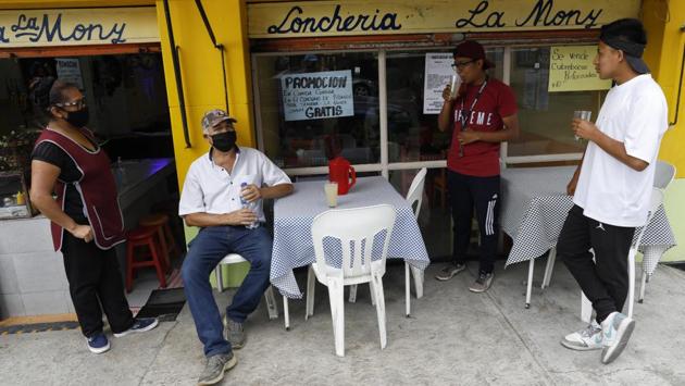 Brothers Cristhian Omar Nanguelu, 17, right, and Alexis De Jesus Nanguelu, 23, chat with the managers of a lunch restaurant, who offered them juice after they performed on the marimba in the street outside, in the Roma Norte neighborhood of Mexico City. (AP Photo/Rebecca Blackwell) Brothers Cristhian Omar Nanguelu, 17, right, and Alexis De Jesus Nanguelu, 23, chat with the managers of a lunch restaurant, who offered them juice after they performed on the marimba in the street outside, in the Roma Norte neighborhood of Mexico City. (AP Photo/Rebecca Blackwell)